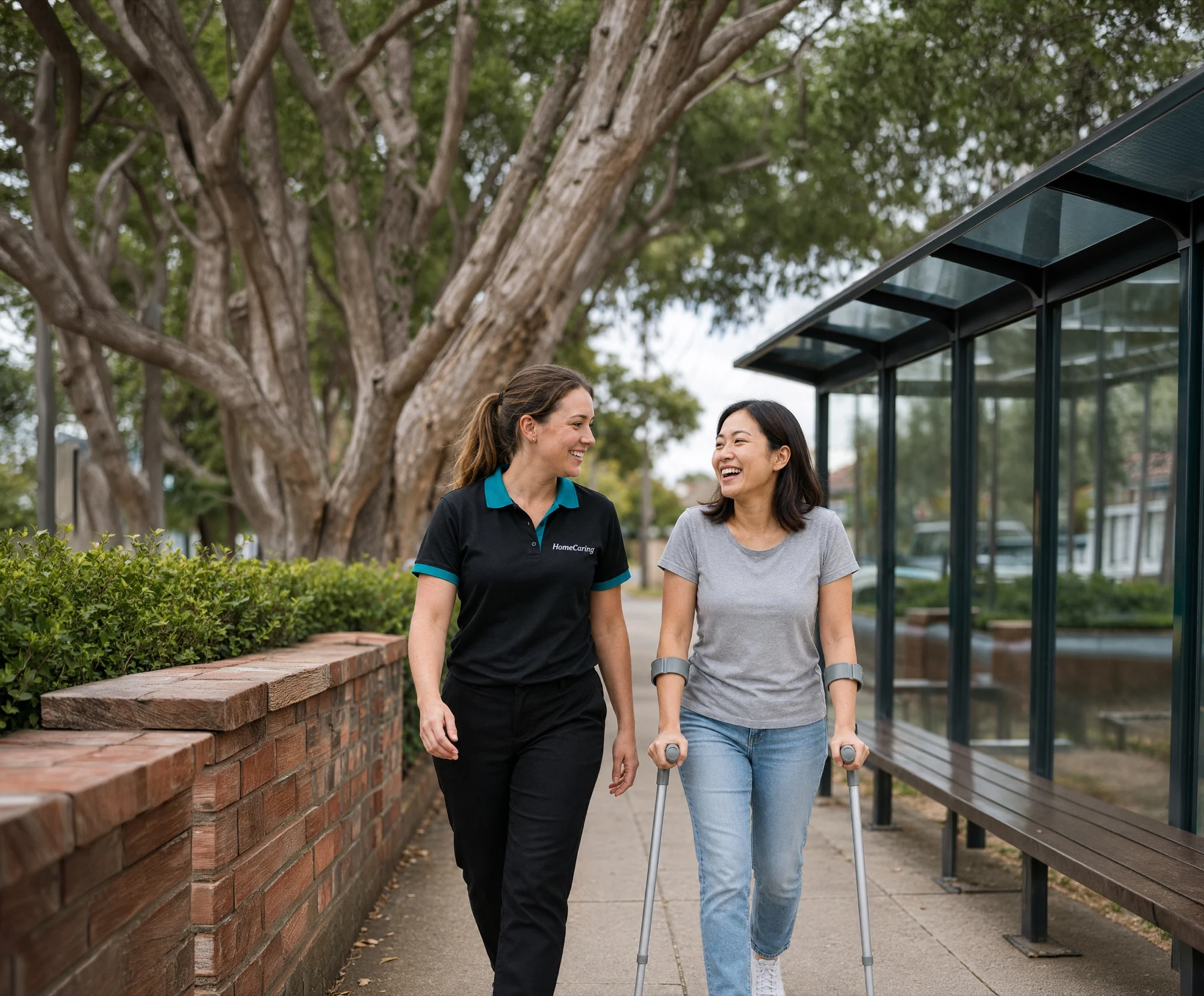 female support worker walking with female ndis client using crutches wearing grey tshirt